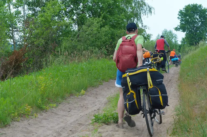 Cyclist wheeling bike up hill with loaded trunk