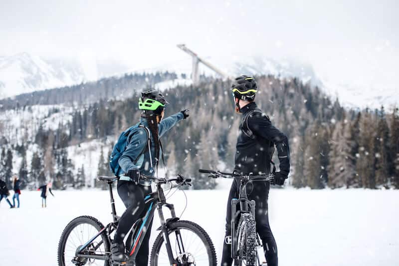 Two mountain bikers resting outdoors in the snow