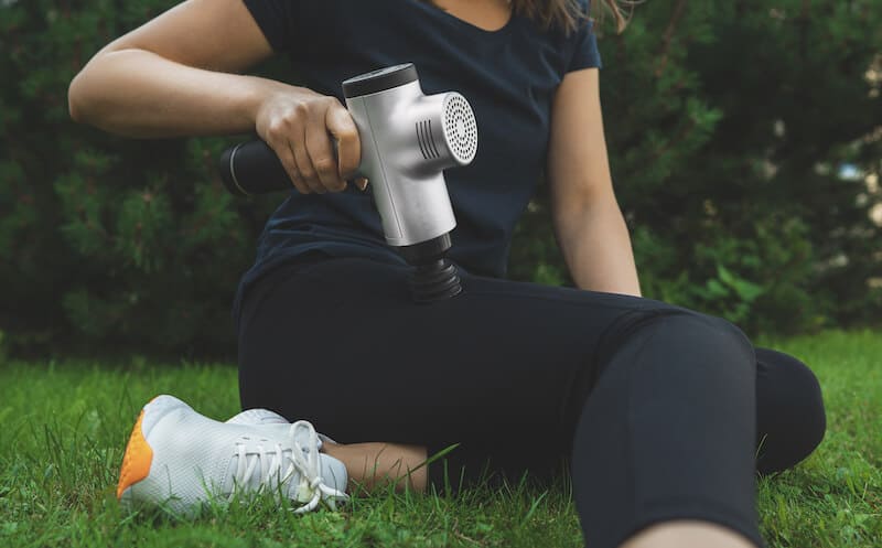 Woman massaging leg with massage gun