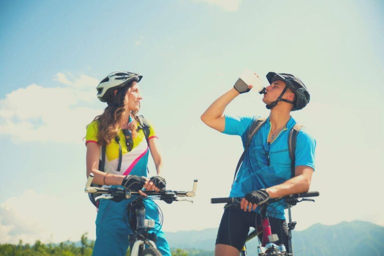 Couple cycling together and man drinking water