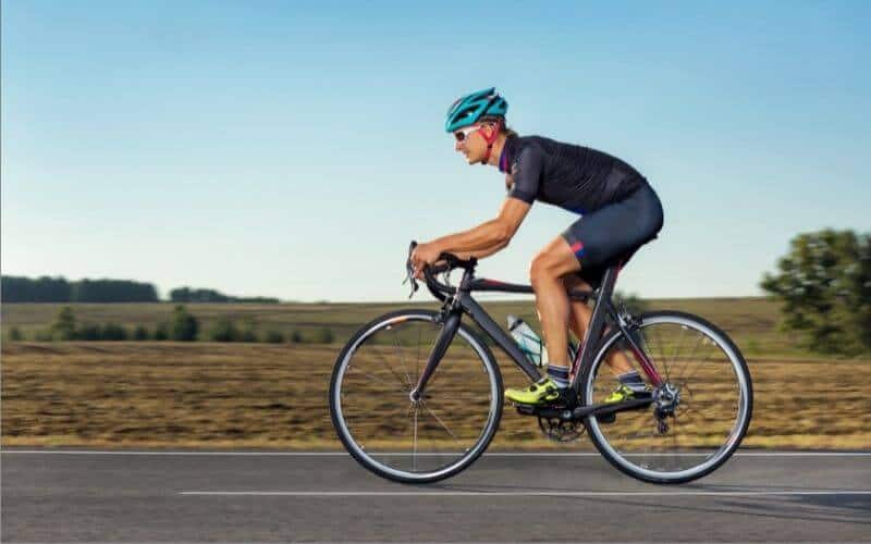 Man riding a road bike along flat road