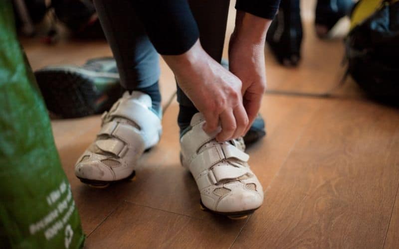 Man putting on white cycling shoes