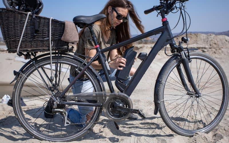 Woman putting electric bike battery into frame