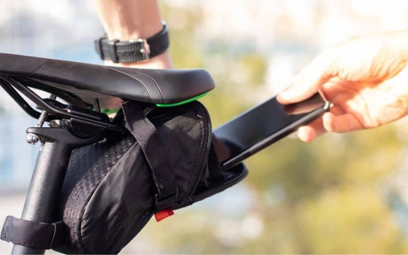 Cyclist putting phone into saddle bag